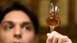 A barman looks at a glass with plum brandy in a bar in Belgrade, Serbia, Friday, Nov. 11, 2022. (AP Photo/Darko Vojinovic)