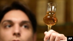 A barman looks at a glass with plum brandy in a bar in Belgrade, Serbia, Friday, Nov. 11, 2022. (AP Photo/Darko Vojinovic)