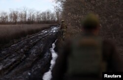 Members of the 68th Independent Jager Brigade of the Ukrainian Army avoid a road bogged down by thick mud next to field positions near the frontline in the Southern Donbas region in Ukraine, Nov. 29, 2022.