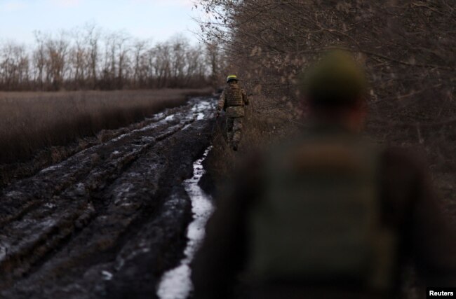 Members of the 68th Independent Jager Brigade of the Ukrainian Army avoid a road bogged down by thick mud next to field positions near the frontline in the Southern Donbas region in Ukraine, Nov. 29, 2022.