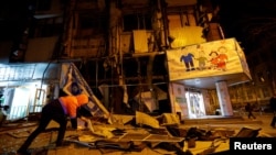 A municipal worker removes debris outside a residential building damaged in shelling in the course of Russia-Ukraine conflict in Donetsk, Russian-controlled Ukraine, Dec. 2, 2022.