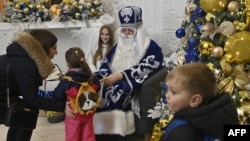 A man dressed as a Saint Nicholas and a woman dressed as an angel greet children at a public library in Irpin, northwest of Kyiv, on Dec. 23, 2022, amid the Russian invasion of Ukraine.