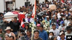 People walk in a funeral procession for Clemer Rojas, 23, who was killed during protests against new President Dina Boluarte, in Ayacucho, Peru, Dec. 17, 2022. 