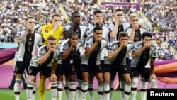 Germany players cover their mouths as they pose for a team group photo before the group E soccer match between Germany and Japan, at the Khalifa International Stadium in Doha, Qatar, Nov. 23, 2022.