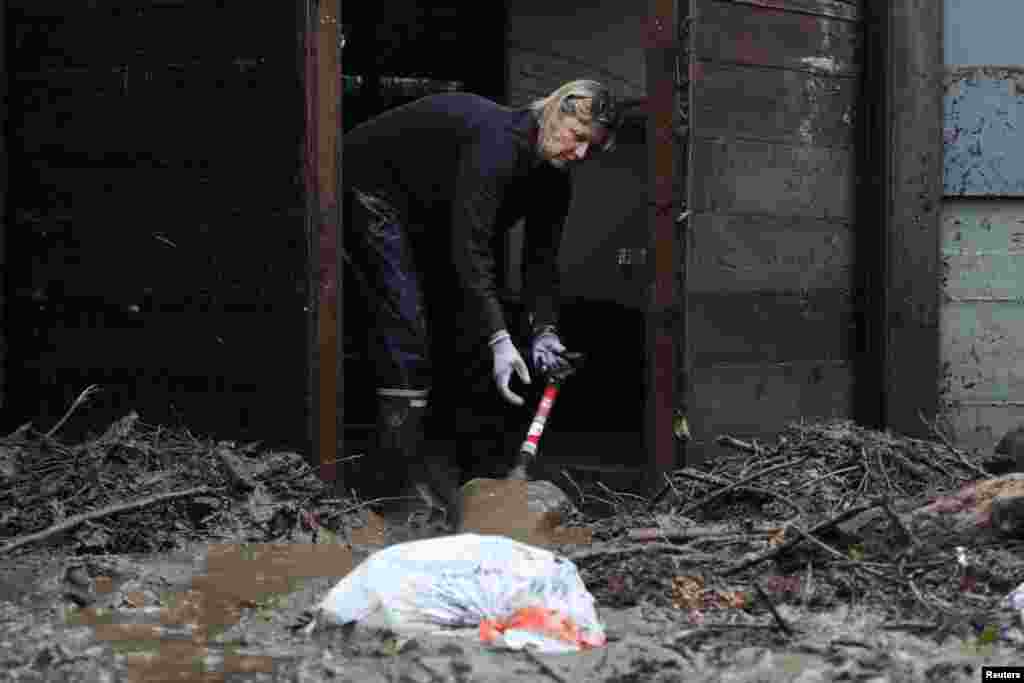 Camilla Shaffer, a resident of Felton, scrapes mud out of her home after major flooding overnight caused by an atmospheric river storm system in Felton, California, Jan. 9, 2023.