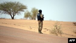 Un gendarme du Burkina Faso monte la garde au bord d'une route.