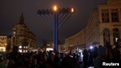 People stand next to a giant menorah during a ceremony for the Jewish festival of Hanukkah, amid Russia’s attacks on Ukraine, at Independence Square in Kyiv, Ukraine, Dec. 18, 2022.