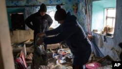 A family look through their possessions at their house which was occupied by Russian forces, in recently liberated village of Pravdyne, Kherson region, Ukraine, Dec. 6, 2022.