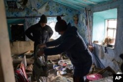 A family look through their possessions at their house which was occupied by Russian forces, in recently liberated village of Pravdyne, Kherson region, Ukraine, Dec. 6, 2022.