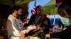 A migrant, center, receives a hot meal from volunteers outside the Sacred Heart Church in downtown El Paso, Texas, Jan. 7, 2023.