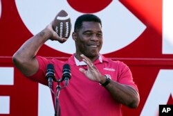 FILE - Republican candidate for U.S. Senate Herschel Walker throws a football to a supporter during a campaign rally Nov. 29, 2022, in Greensboro, Ga. Walker is in a runoff election with incumbent Democratic Sen. Raphael Warnock.