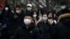 Commuters wearing face masks walk along a street in the central business district of Beijing, Jan. 12, 2023. A new study says roughly 64% of all people in China are estimated to have been infected with COVID.