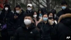 Commuters wearing face masks walk along a street in the central business district of Beijing, Jan. 12, 2023. A new study says roughly 64% of all people in China are estimated to have been infected with COVID.