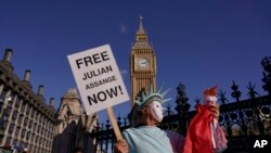 FILE - Seseorang pendukung Julian Assange di London, memegang plakat sebagai aksi protes ekstradisi pendiri WikiLeaks itu ke AS, 8 Oktober 2022. (AP/Alberto Pezzali, File)