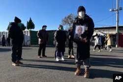 北京一家火葬场外死者亲属手捧亲人的照片。（2022年12月17日）