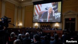 Members of the U.S. House Select Committee investigating the January 6 attack on the U.S. Capitol sit beneath an image showing former President Donald Trump in the Oval Office, at the U.S. Capitol in Washington, D.C., Dec. 19, 2022.