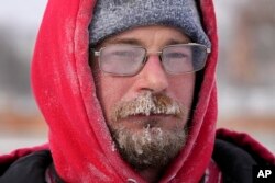 Mark Sorter's face is seen covered in snow and ice as he clears snow from a downtown ice skating rink, Dec. 23, 2022, in Des Moines, Iowa.