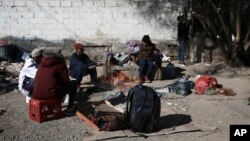 Migrants sit around a fire at a shelter on the U.S.-Mexico border in Ciudad Juarez, Mexico, Dec. 19, 2022.