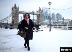 Warga berjalan di jalanan yang tertutup salju di dekat Tower Bridge, London, Inggris, 12 Desember 2022. (REUTERS/Henry Nicholls)