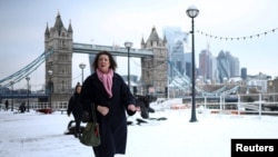 People walk on a snow-covered pathway near the Tower Bridge, as cold weather continues in London, Dec. 12, 2022.