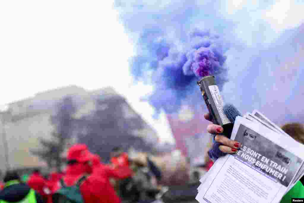 A person holding a smoke grenade takes part in a demonstration against the rising cost of living, in Brussels, Belgium.