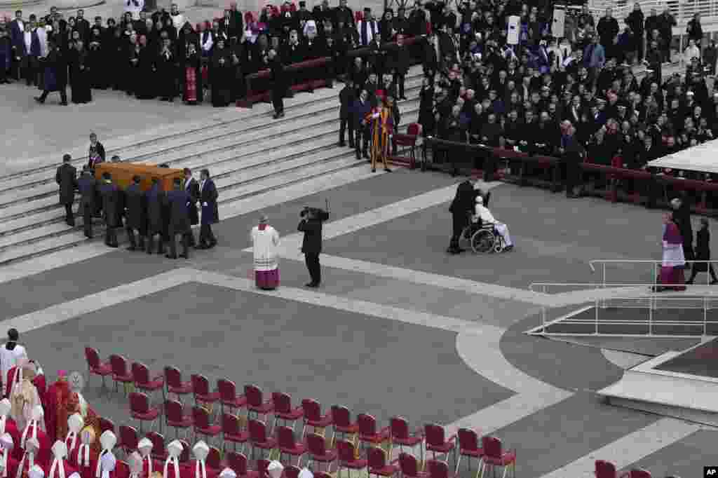 Pope Francis is pushed away on a wheelchair while the coffin of late Pope Emeritus Benedict XVI is carried away after a funeral mass in St. Peter&#39;s Square, Jan. 5, 2023.