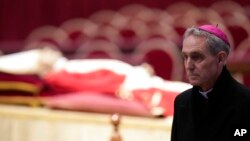 The body of late Pope Emeritus Benedict XVI laid out in state as Archbishop Georg Gaenswein stands on the right inside St. Peter's Basilica at The Vatican, Jan. 2, 2023. 