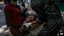 FILE - A youth suffering from cholera is helped upon arrival at a clinic run by Doctors Without Borders in Port-au-Prince, Haiti, on Oct. 27, 2022.