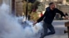 Seorang demonstran Palestina melempar tabung gas air mata yang ditembakkan pasukan Israel menyusul protes terhadap perampasan tanah Palestina oleh Israel di Tepi Barat, di Desa Kfar Qaddum, dekat pemukiman Yahudi Kedumim pada 6 Januari, 2023. (Foto: AFP)