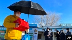 一名男子手捧亲人骨灰盒走出一家北京火葬场。（2022年12月17日）