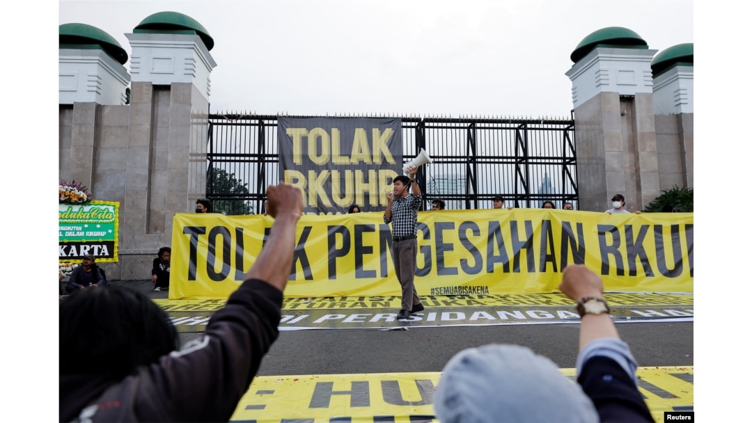 Seorang aktivis meneriakkan slogan-slogan saat protes pengesahan hukum pidana baru yang akan melarang seks di luar nikah, kumpul kebo antara pasangan yang belum menikah, menghina presiden, dan mengungkapkan pandangan yang bertentangan dengan ideologi nasional, di luar gedung DPR RI di Jakarta, 5 Desember 2022. (Foto: REUTERS/Willy Kurniawan)