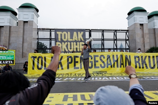 Seorang aktivis meneriakkan slogan-slogan saat protes pengesahan hukum pidana baru yang akan melarang seks di luar nikah, kumpul kebo antara pasangan yang belum menikah, menghina presiden, dan mengungkapkan pandangan yang bertentangan dengan ideologi nasional, di luar gedung DPR RI di Jakarta, 5 Desember 2022. (Foto: REUTERS/Willy Kurniawan)