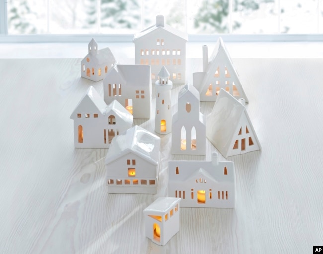 This image provided by Crate & Barrel shows their collection of white ceramic buildings. Crate & Barrel's collection includes alpine homes and hotels as well as midcentury split levels and ranch homes. Add a tealight for a welcoming glow. (Crate & Barrel via AP)