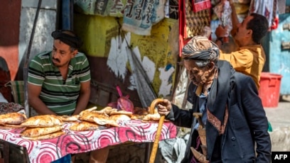 FILE - An elderly man walks past a peddler selling bread in a market in Taez, Yemen, Oct. 4, 2022. A truce in the Yemeni civil war lapsed two days earlier, yet peace has largely held since then.