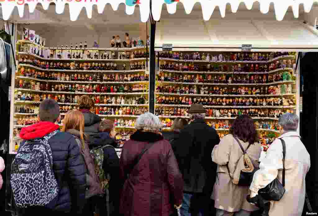 En la Feria de Navidad de Santa Lucía, en Barcelona, personas se acercan a mirar figurillas de &quot;caganers&quot;, uno de los elementos más tradicionales de los pesebres en la zona de Cataluña, en el noreste de España.