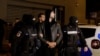 Andrew Tate and Tristan Tate are escorted by police officers outside the headquarters of the Directorate for Investigating Organized Crime and Terrorism in Bucharest (DIICOT) after being detained for 24 hours, in Bucharest, Romania, Dec. 29, 2022. 
