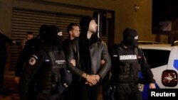 Andrew Tate and Tristan Tate are escorted by police officers outside the headquarters of the Directorate for Investigating Organized Crime and Terrorism in Bucharest (DIICOT) after being detained for 24 hours, in Bucharest, Romania, Dec. 29, 2022. 