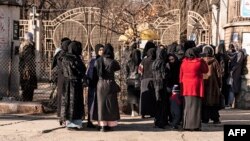 FILE - Afghan female university students are stopped by Taliban security personnel next to a university in Kabul, Dec. 21, 2022.