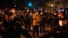 Osoba iz osiguranja u civilnoj odjeći razgovara na telefon dok formira redove policajaca da blokiraju demonstrante u Pekingu 27. studenog 2022.