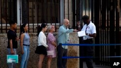 People stand in line outside the U.S. embassy on the day of its reopening for visa and consular services in Havana, Cuba, Jan. 4, 2023.