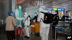 身穿防护服的防疫人员在北京首都机场给旅客指导行走方向（美联社2022年12月13日照片）