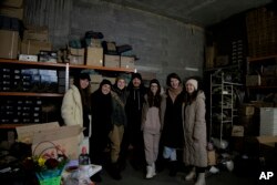 Ukrainian soldier Anastasia Mokhina, third left, and co-founders Kseniia Drahaniuk, third right, and husband Andrii Kolesnyk, center, of the nonprofit group Zemliachky in Kyiv, Ukraine, on Tuesday, Dec. 6, 2022. (AP Photo/Vasilisa Stepanenko)