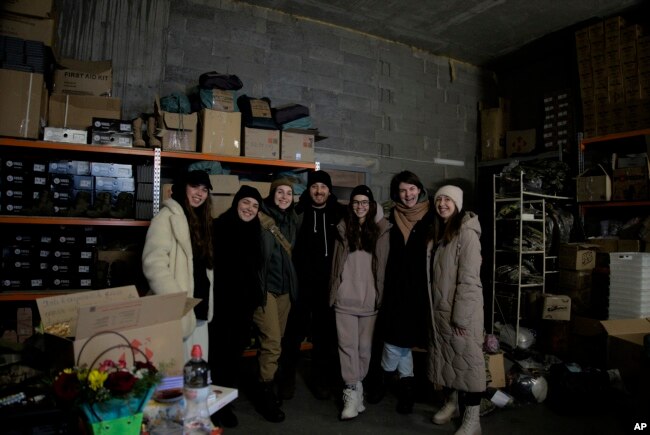 Ukrainian soldier Anastasia Mokhina, third left, and co-founders Kseniia Drahaniuk, third right, and husband Andrii Kolesnyk, center, of the nonprofit group Zemliachky in Kyiv, Ukraine, on Tuesday, Dec. 6, 2022. (AP Photo/Vasilisa Stepanenko)