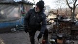 A man grinds grain to make food for his animals as artillery fire can be heard near his land where he and his wife live despite the fact that their home was mostly destroyed in the summer and their garden was hit as recently as last week, in Siversk, Ukraine, Nov. 30, 2022.