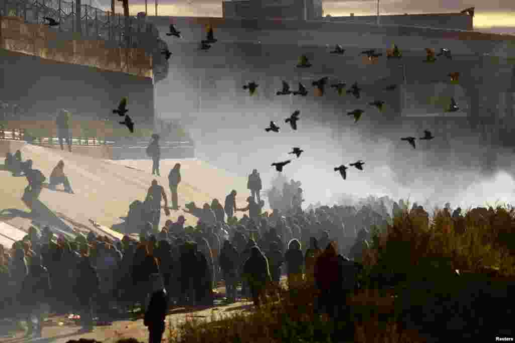 Migrants queue near the border wall after crossing the Rio Bravo river to turn themselves in to U.S. Border Patrol agents to request asylum in the U.S. city of El Paso, Texas, Dec. 13, 2022.