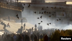 Migrants queue near the border wall after crossing the Rio Bravo river to turn themselves in to U.S. Border Patrol agents to request asylum in the U.S. city of El Paso, Texas, Dec. 13, 2022.