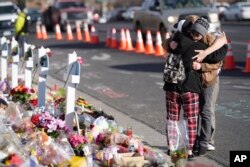 FILE - Visitors hug while looking over a makeshift memorial near the scene of a mass shooting at a gay nightclub, in Colorado Springs, Colorado, Nov. 23, 2022.