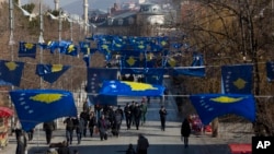 FILE - Kosovo's flags fly in Pristina as police officers patrol during a celebration of the country's independence, Feb. 17, 2020.