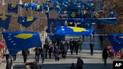 FILE - Kosovo's flags fly in Pristina as police officers patrol during a celebration of the country's independence, Feb. 17, 2020.