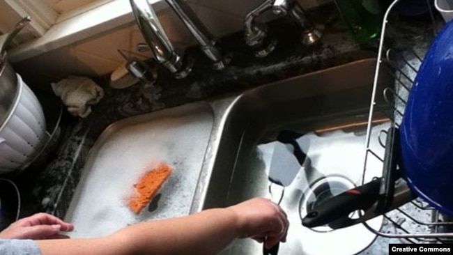 Washing dishes in a sink.